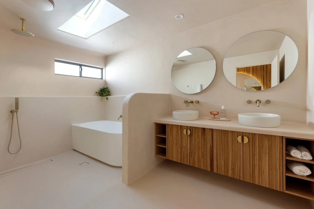 Curved bathroom finished in warm stone and natural textures